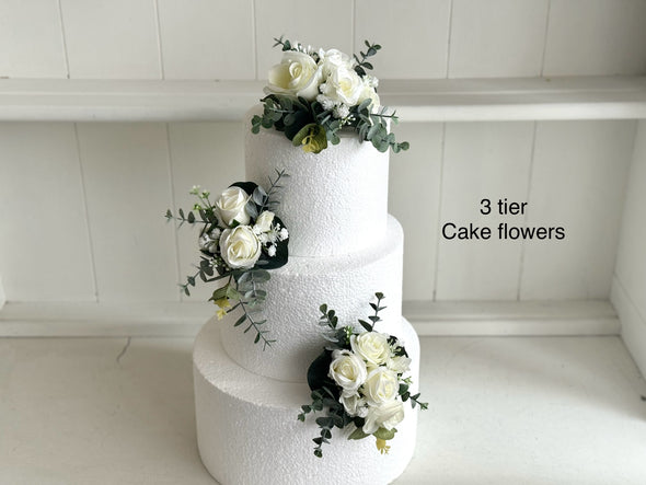 White and green cake flowers, wedding cake decoration including white roses, gypsophila and eucalyptus.